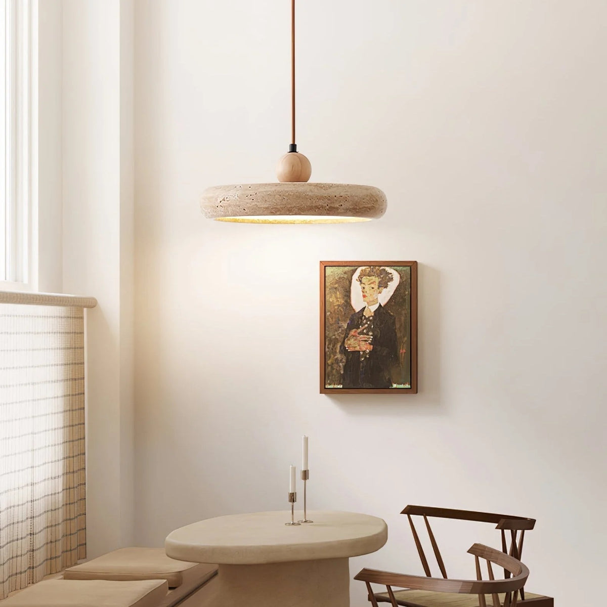 Terra travertine disc pendant light over a dining nook with framed artwork