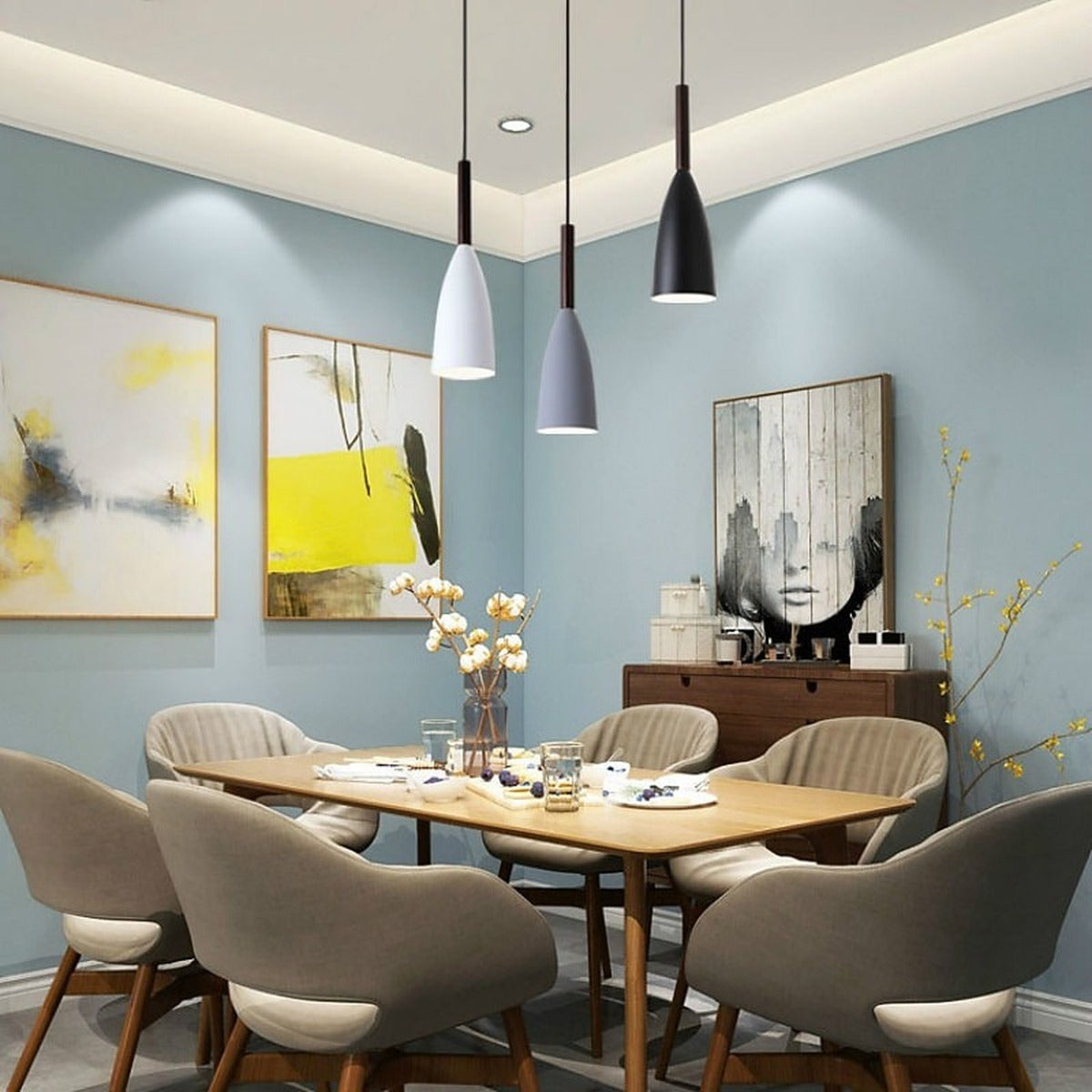 Three single Vika slim pendant lights in white, gray and black over a wood dining table with a blue wall